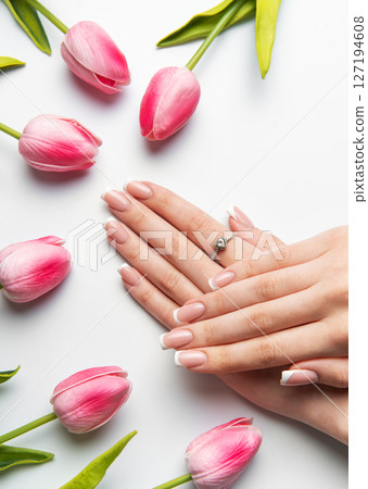 Woman showing french manicure near pink tulips on white background Woman showing french manicure near pink tulips on white background 127194608
