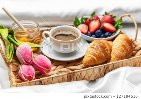 Romantic breakfast in bed with coffee, croissants, berries, honey and tulips 127194616