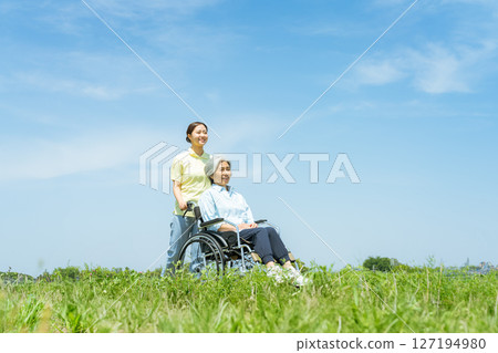 A caregiver pushing a wheelchair 127194980