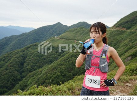 A runner drinking water during a break during trail running 127195126