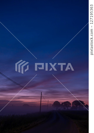 A Beautiful and Tranquil Dawn Unfolds Over a Misty Road in the Picturesque Countryside A Beautiful and Tranquil Dawn Unfolds Over a Misty Road in the Picturesque Countryside 127195363
