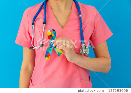 World Autism awareness and pride day with Puzzle pattern ribbon. The doctor's hand World Autism awareness and pride day with Puzzle pattern ribbon. The doctor's hand 127195606