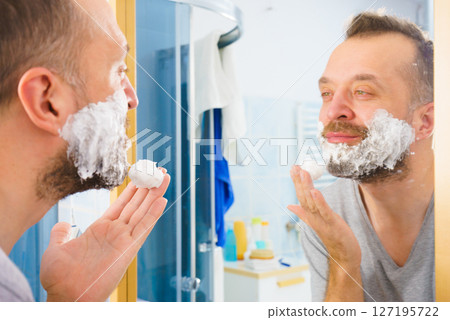 Guy shaving his beard in bathroom 127195722
