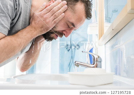 Man washing his face in bathroom 127195728