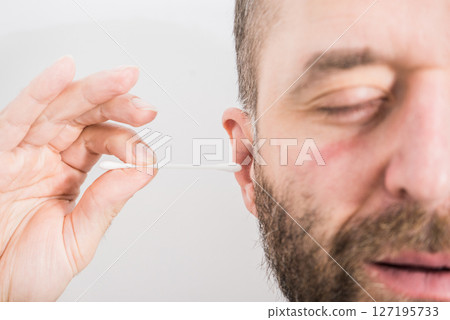 Man removing wax from ear using Q-tip 127195733