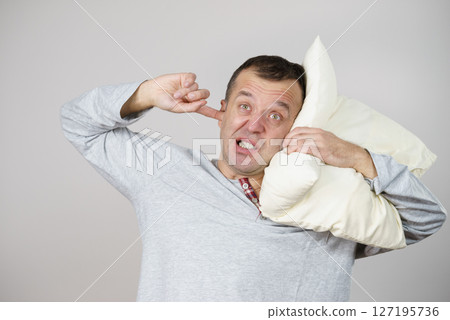 Sleepy man with pillow closing his ear Sleepy man with pillow closing his ear 127195736