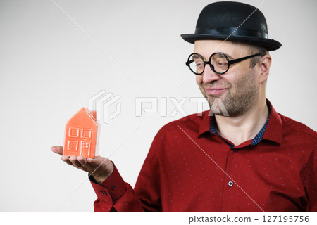 Man wearing funny eyeglasses holding house Man wearing funny eyeglasses holding house 127195756