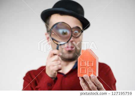 Man magnifying red house Man magnifying red house 127195759
