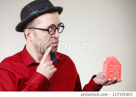 Man wearing funny eyeglasses holding house 127195801