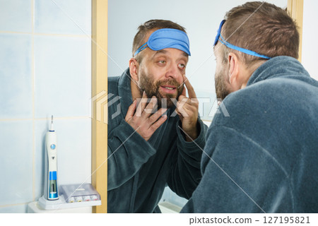 Sleepy man looking at mirror 127195821
