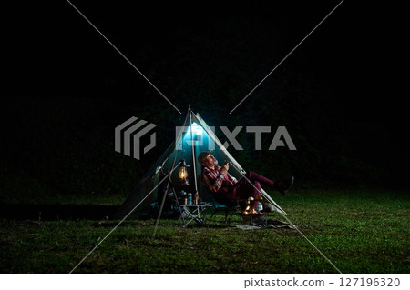 Solo camper drinking alcohol while looking up at the night sky Solo camp Senior Solo camper drinking alcohol while looking up at the night sky Solo camp Senior 127196320