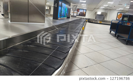 Lisbon Airport; Vertical shot; Selective focus on a single bag in the luggage claim area, standing out against the grey floor. The indoor setting with white lights adds to the atmosphere 127196786