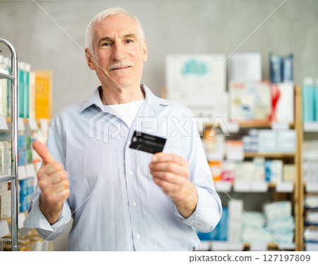Elderly man with credit card chooses products in pharmacy 127197809