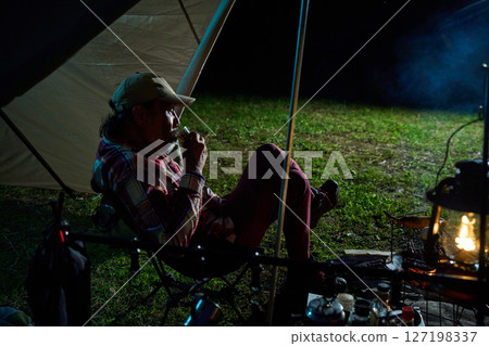 Solo camper drinking alcohol, solo camping, senior 127198337