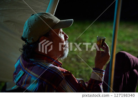 Solo camper drinking alcohol, solo camping, senior Solo camper drinking alcohol, solo camping, senior 127198340
