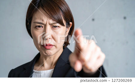 Angry businesswoman pointing her finger (AI-generated image) 127200269