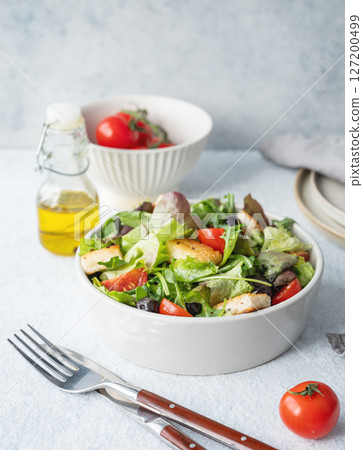 Vegetarian salad with lettuce, tomatoes, croutons and olives in a bowl on a light background Vegetarian salad with lettuce, tomatoes, croutons and olives in a bowl on a light background 127200499