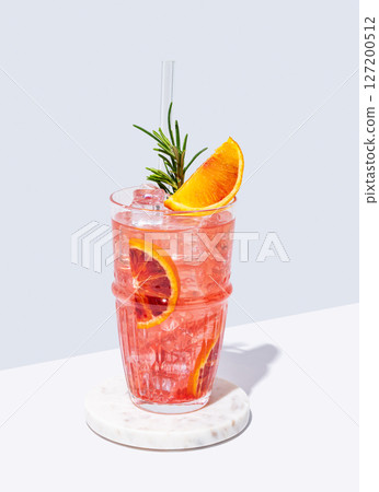 Blood orange cocktail with ice and rosemary on a marble stand on a white blue background 127200512