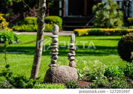 Decorative vertical stone sculptures in spring in a beautiful green garden in the city. Decorative vertical stone sculptures in spring in a beautiful green garden in the city. 127201097