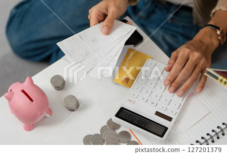 Financial Planning. Individual calculating expenses with receipts and a calculator. 127201379