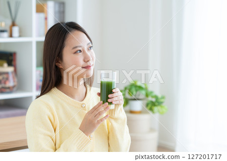 A young woman drinking green juice 127201717