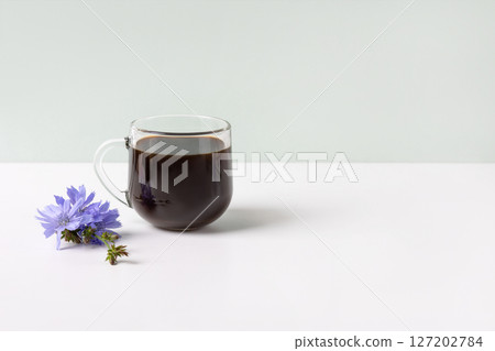 Glass cup with chicory drink and blue chicory flowers on gray background. Healthy eating Glass cup with chicory drink and blue chicory flowers on gray background. Healthy eating 127202784