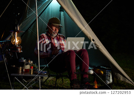 Solo camper working on a computer, Solo camping, Senior 127202953