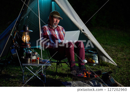 Solo camper working on a computer, Solo camping, Senior 127202960