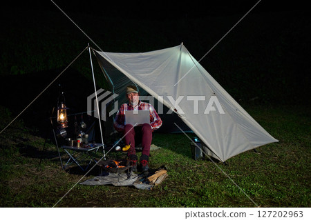 Solo camper working on a computer, Solo camping, Senior Solo camper working on a computer, Solo camping, Senior 127202963