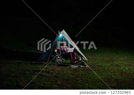 Solo camper working on a computer, Solo camping, Senior 127202965