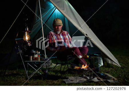 Solo camper working on a computer, Solo camping, Senior Solo camper working on a computer, Solo camping, Senior 127202976