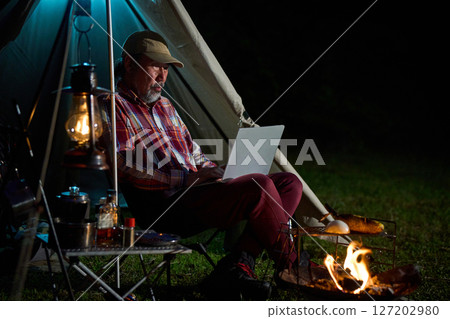 Solo camper working on a computer, Solo camping, Senior 127202980