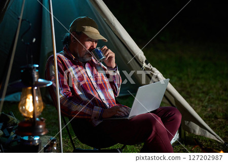 Solo camper working on a computer, Solo camping, Senior 127202987