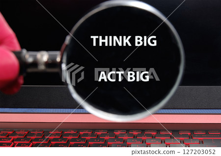 THINK BIG ACT BIG concept words through a magnifying glass on a laptop screen in a dimly lit room THINK BIG ACT BIG concept words through a magnifying glass on a laptop screen in a dimly lit room 127203052