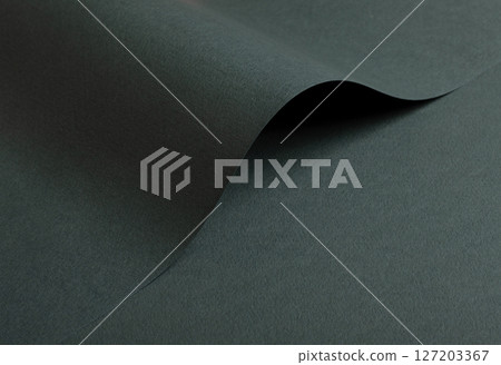Dark green matte paper texture with a premium, elegant finish, featuring wavy folds and edges. 127203367