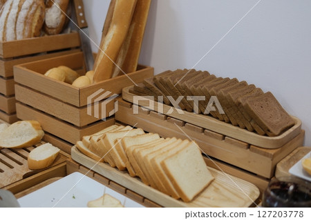 Freshly baked bread in wicker baskets. Rustic bread display in bakery. Handmade loaves with crusty surface. Artisanal bread selection. Traditional baking background. Warm and cozy shop scene. Freshly baked bread in wicker baskets. Rustic bread display in bakery. Handmade loaves with crusty surface. Artisanal bread selection. Traditional baking background. Warm and cozy shop scene. 127203778