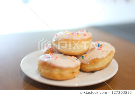 a woman's hand takes a donut from a plate, bites off a piece and puts it back a delicious dessert 127203853