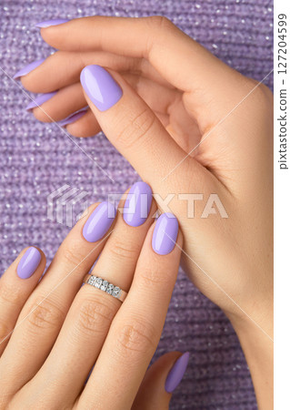 Manicured womans hands on violet knitted fabric. Manicure, pedicure beauty salon concept Manicured womans hands on violet knitted fabric. Manicure, pedicure beauty salon concept 127204599