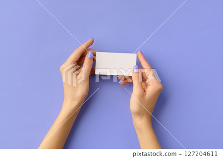 Womans hands holding business card on purple background. Business work template mockup 127204611