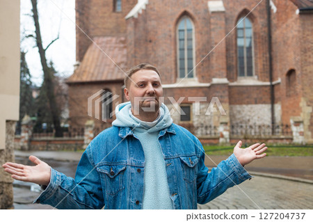 Man Shrugs Under Rainy Skies in Historic Town 127204737