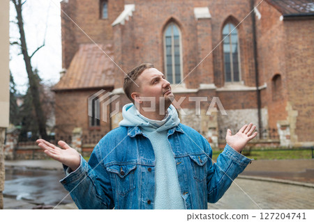 Man Shrugging Outdoors in Front of Historic Building 127204741