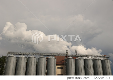 Row of silos are lined up in front of a cloudy sky 127204994