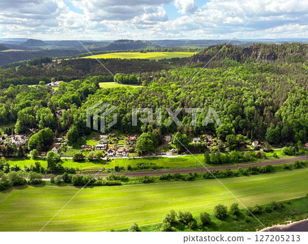 Aerial view of green meadow, village and small river. Cloud shadow falls on green meadows. Aerial view of green meadow, village and small river. Cloud shadow falls on green meadows. 127205213
