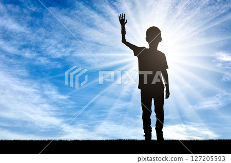A silhouette of a disabled boy with a prosthetic arm, highlighted by the sun shining in the background 127205593