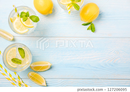 Cold refreshing summer drink with lemon and mint on light blue wooden background, top view, flat lay, copy space. Cold refreshing summer drink with lemon and mint on light blue wooden background, top view, flat lay, copy space. 127206095