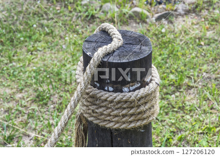 From a wooden bar sticks out a hook with an attached chain From a wooden bar sticks out a hook with an attached chain 127206120