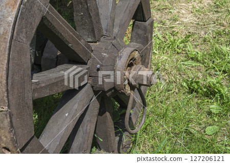 Mounting an old wooden wheel on a rural cart, close - up 127206121