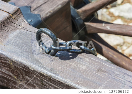 From a wooden bar sticks out a hook with an attached chain 127206122
