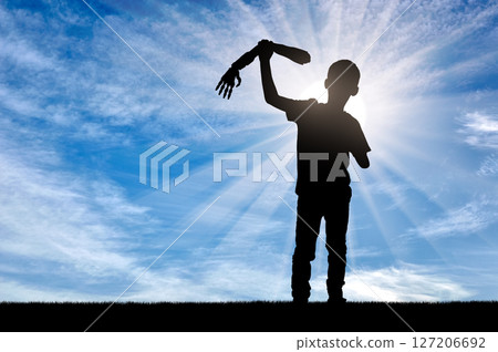 Silhouette of a disabled child holding a prosthetic arm against a bright, sunlit sky Silhouette of a disabled child holding a prosthetic arm against a bright, sunlit sky 127206692