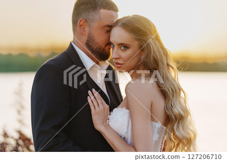 Gentle and happy bride and groom at sunset on the riverbank. Romantic. 127206710